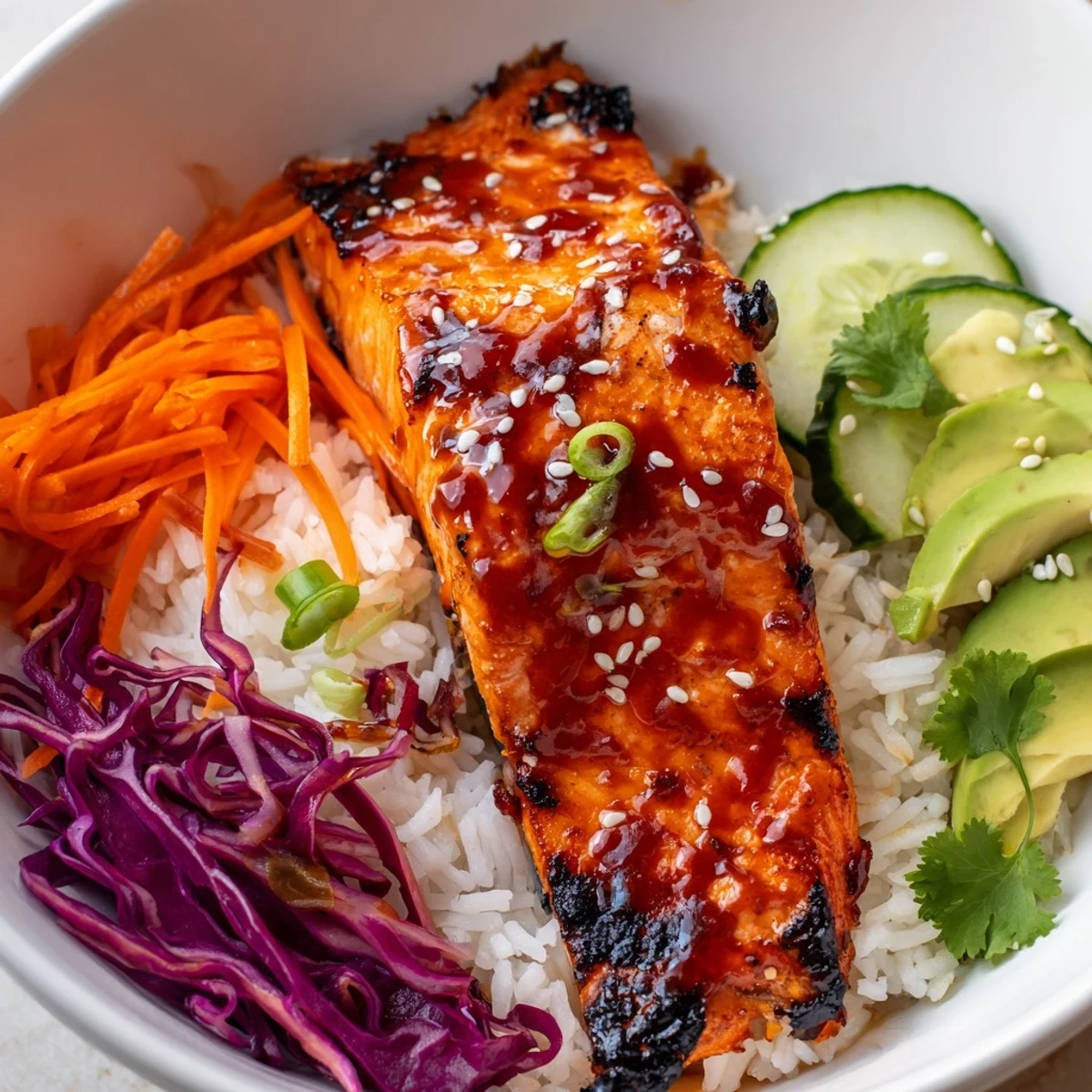 Caramelized Sriracha Honey Glazed Salmon Bowls garnished with avocado and sesame seeds