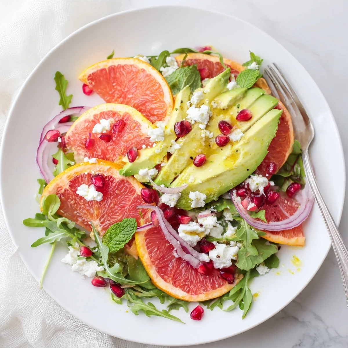 Colorful Mediterranean citrus salad drizzled with olive oil dressing, garnished with fresh mint leaves