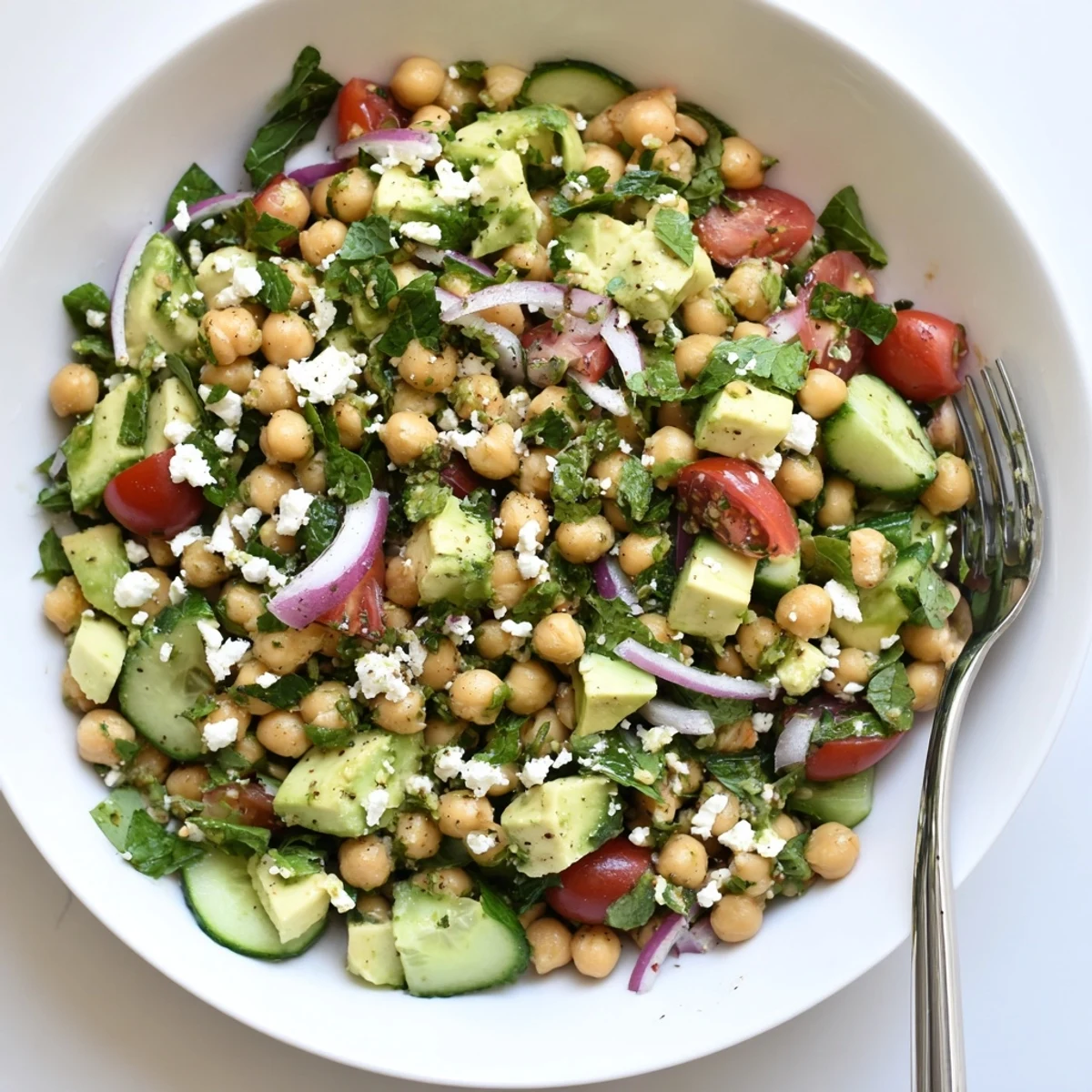 Creamy chickpea feta avocado salad served in a rustic wooden bowl with lemon dressing