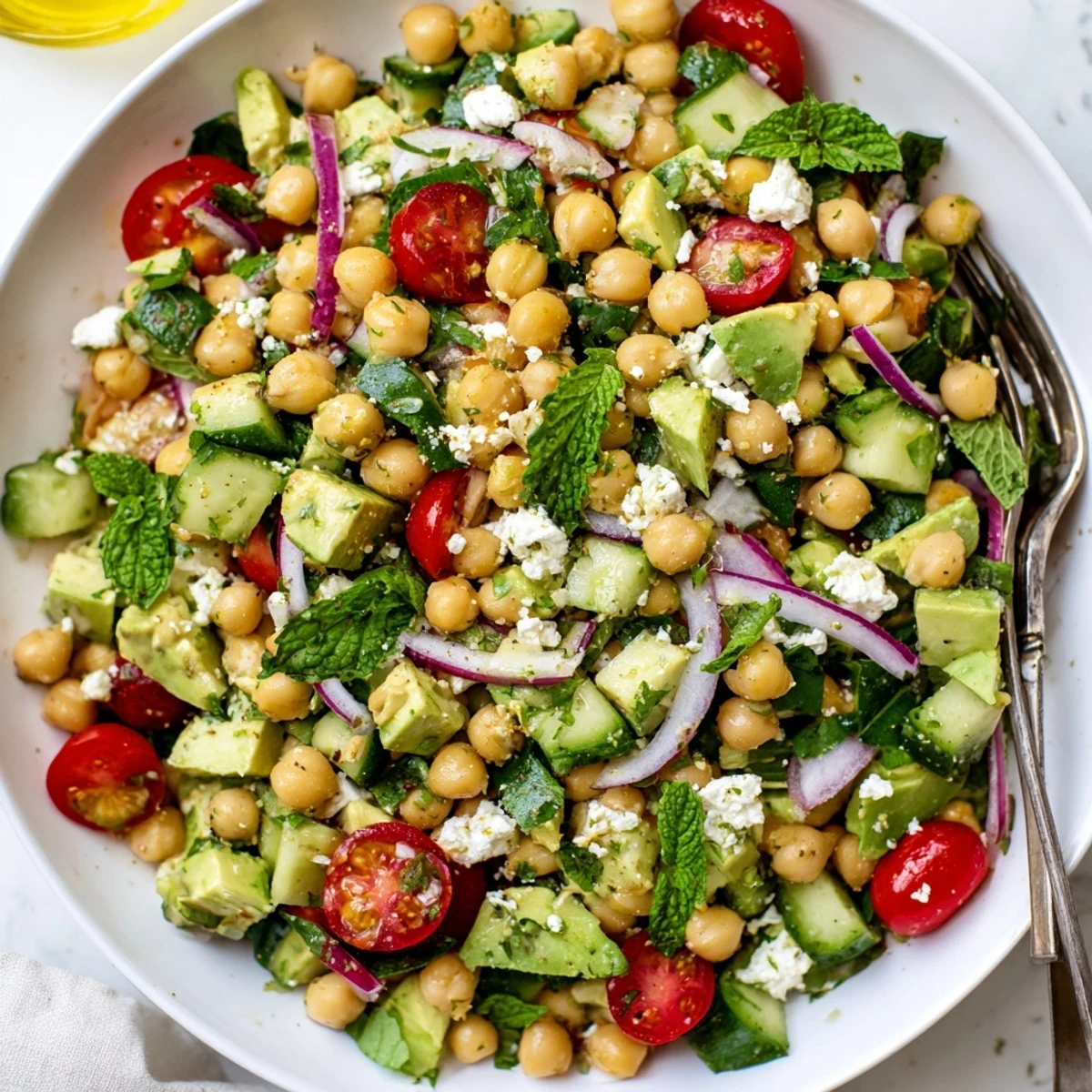 Colorful chickpea feta avocado salad piled on greens with a zesty citrus vinaigrette
