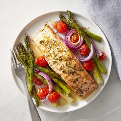 Lemon-garlic salmon, crisp asparagus, and juicy cherry tomatoes roasted on a single sheet pan for a quick dinner.