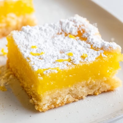 Tangy lemon bars cut into squares showing off the creamy yellow filling